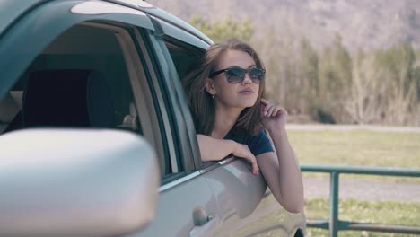 attractive-woman-waves-hand-from-auto-salon-at-green-field