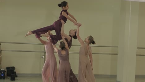 a group of young ballet students in black dancewear practicing positions in a spacious ballet studio with wooden flooring and wall-mounted barres. focused expressions and synchronized movements.