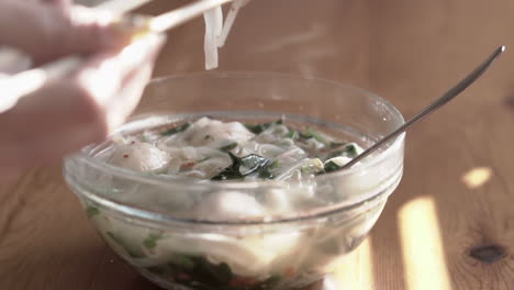 Close-up-video-grabbing-and-eating-meatballs-and-rice-noodles-from-a-very-hot-asian-soup-using-chopsticks