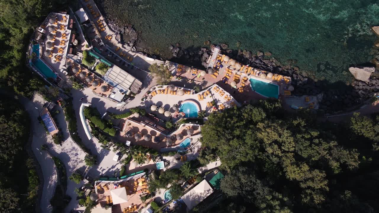 vista panorámica de un spa resort con piscinas climatizadas y muchas sombrillas junto al mar mediterráneo durante un caluroso día de verano ubicado en la isla tropical de ischia frente a la costa de nápoles en italia