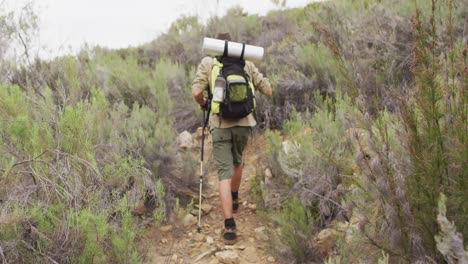 hombre caucásico de supervivencia caminando por el desierto con mochila y palos de caminata