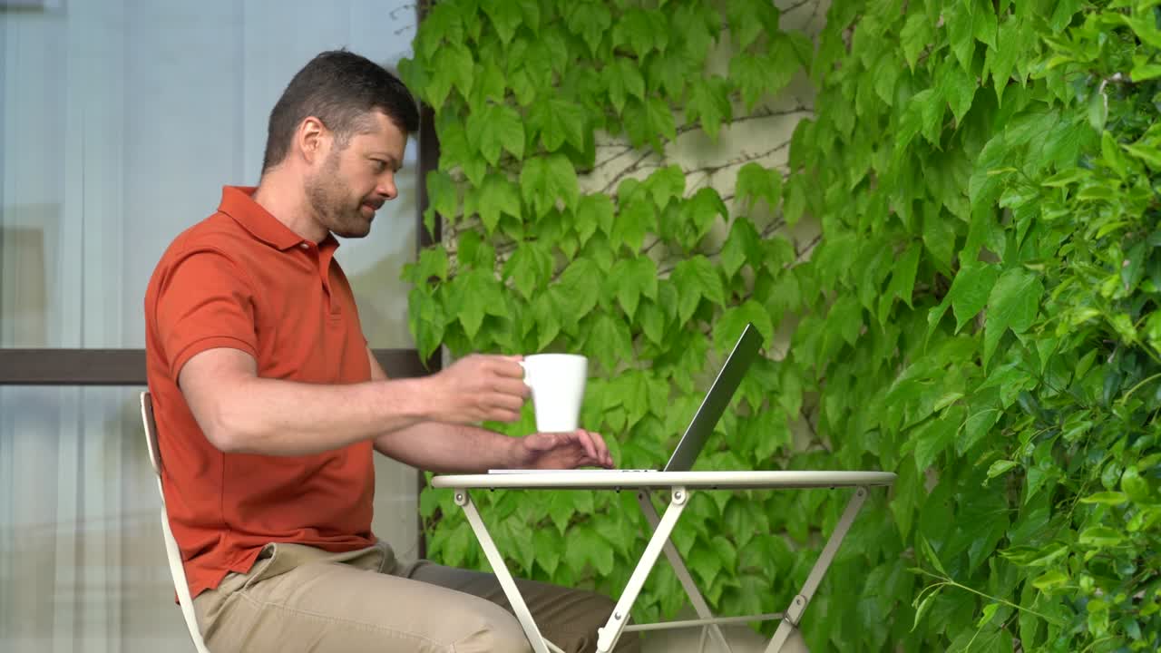 Man works on a laptop on the terrace