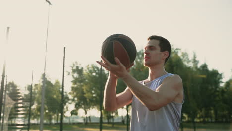 Ein-Lächelnder-Basketballspieler,-Der-Versucht,-Bei-Sonnenuntergang-Auf-Einem-Basketballplatz-Im-Freien-Den-Ball-Auf-Seinem-Finger-Zu-Drehen