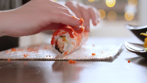 making sushi at home kitchen. woman hands rolling homemade sushi.