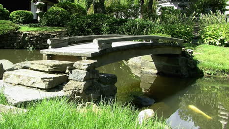 Fußgängerbrücke-überspannt-Einen-Teich-In-Einem-Japanischen-Garten