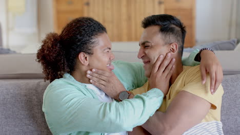 una pareja gay feliz y diversa haciendo una llamada de video y abrazándose en casa, en cámara lenta
