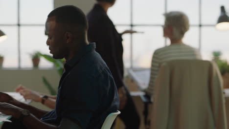 young black businessman using computer typing developing creative design for company project in busy office background