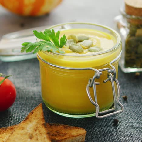 Creamy-pumpkin-soup-in-jar-with-bread-and-tomatoes
