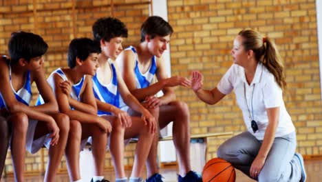 female coach giving high five to students in basketball court