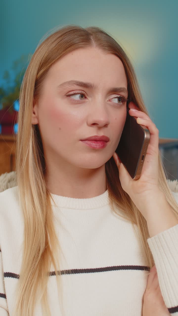 Caucasian woman sitting on sofa at home shocked and sad after receiving bad news on smartphone