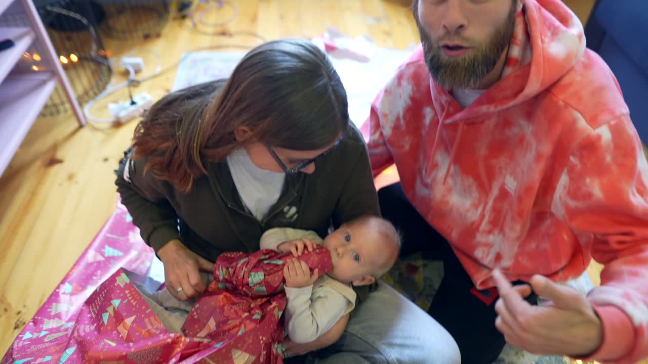 행복 한 가족 이 아기 를 위한 크리스마스 선물 을 풀고 있다