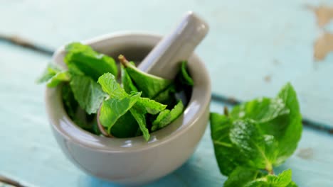 Mint-leaves-with-mortar-and-pestle-on-wooden-table-4k