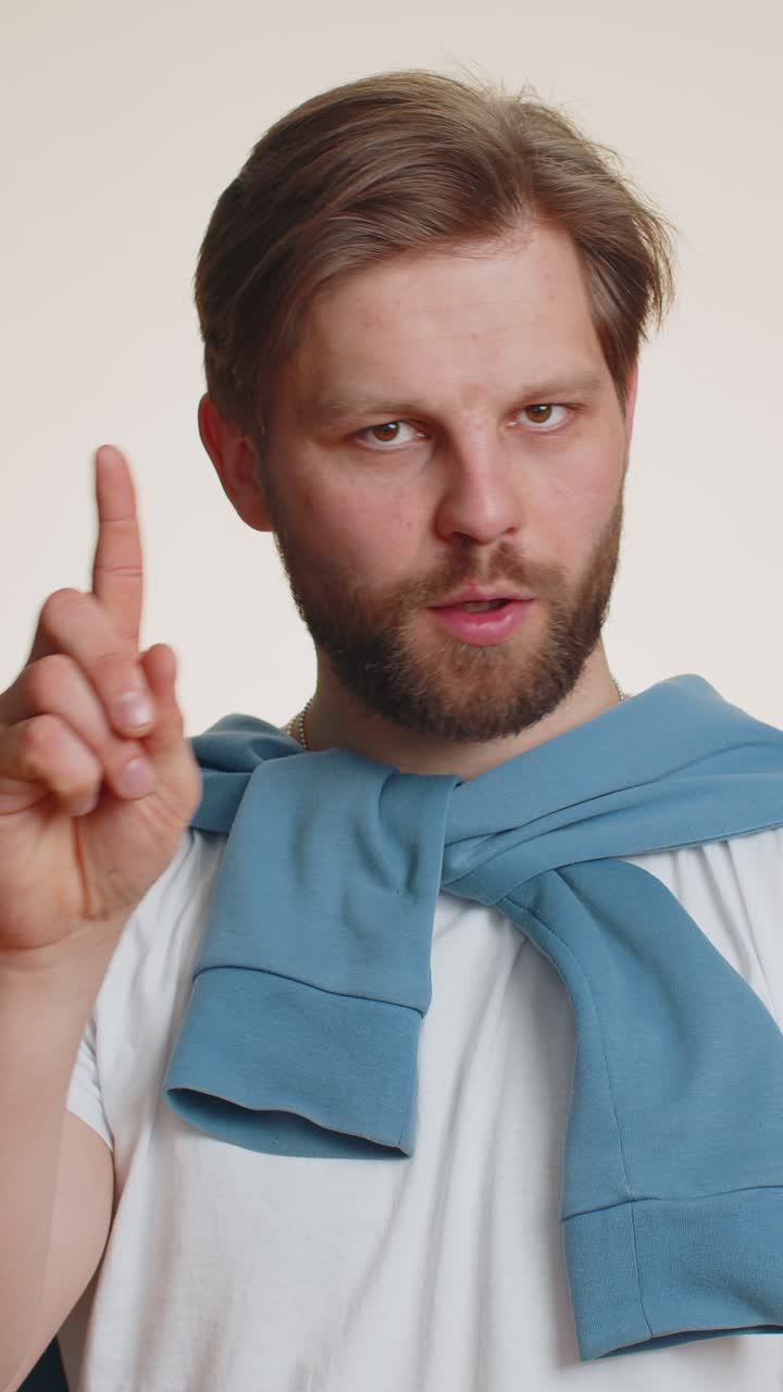 Caucasian young man shakes finger and saying no be careful avoid danger mistake disapproval sign
