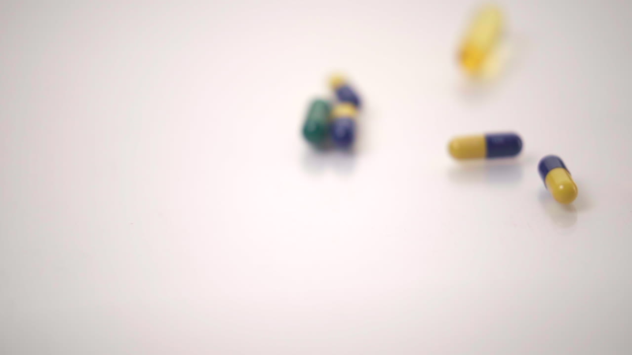 macro de cámara lenta de variedades de píldoras caídas sobre fondo blanco