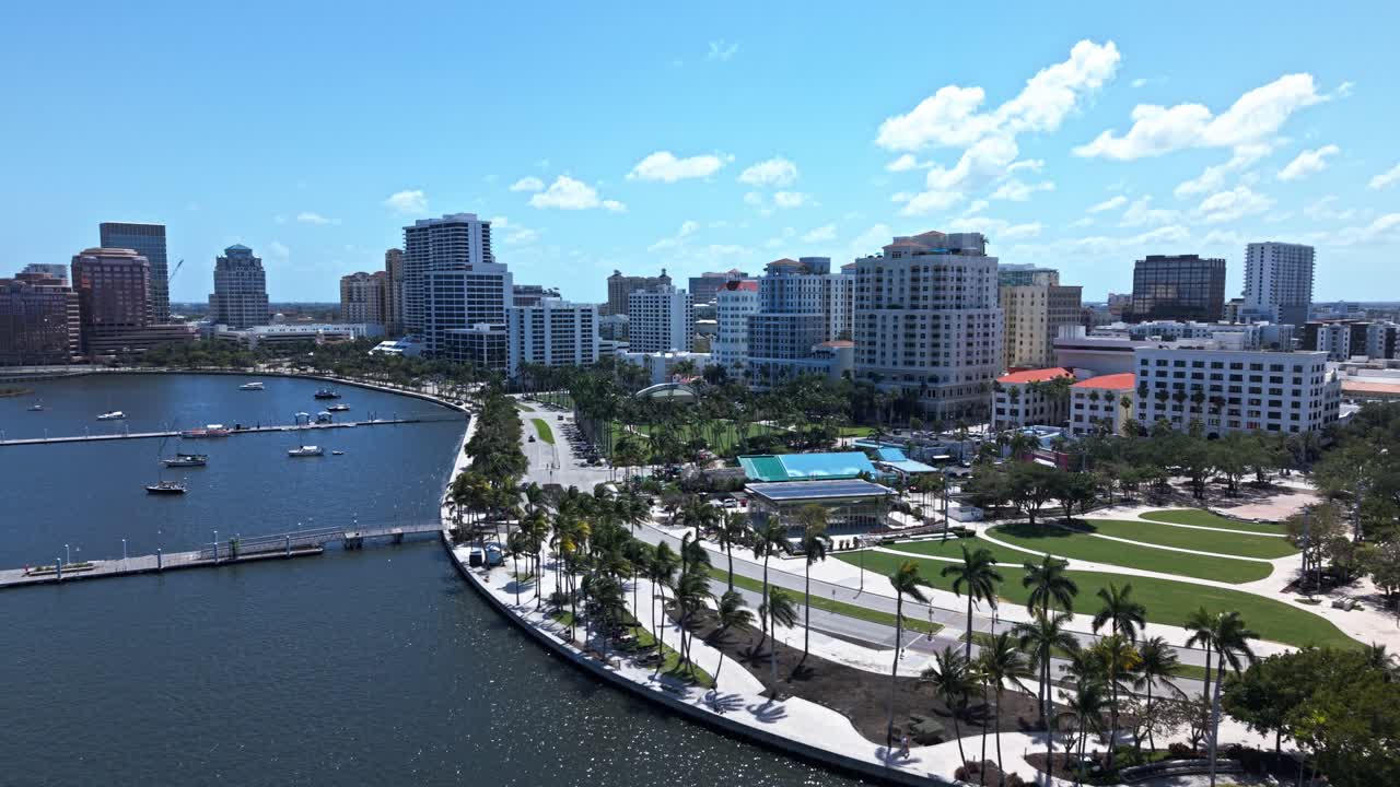 Aerial: downtown West Palm Beach cityscape with Atlantic Ocean and palm trees during the day in Florida, USA, push in drone shot