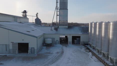 snowy fertilizer plant with silos and industrial equipment, aerial