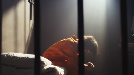 desperate inmate sitting on bed, feeling anger and anguish in prison cell