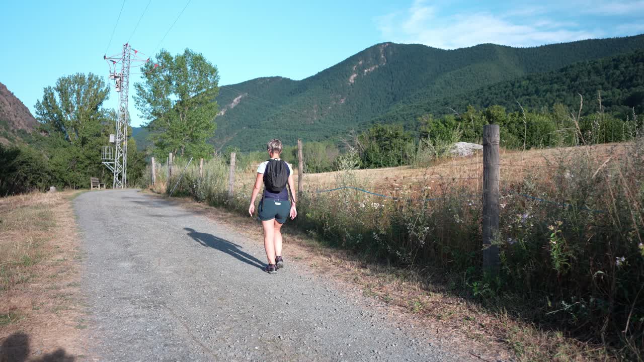 Donna che fa escursionismo su un sentiero in una valle con montagne sullo sfondo