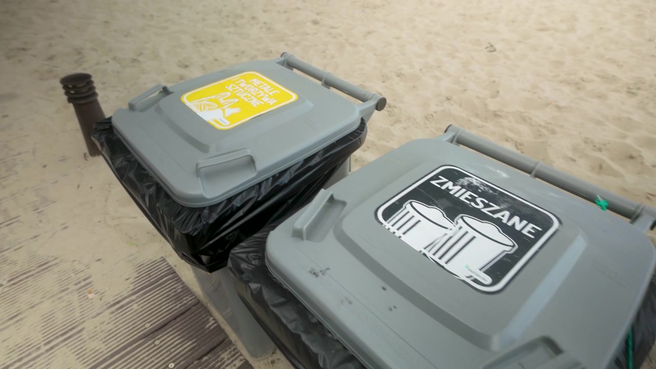 Close up of color coded recycling bins for paper plastic and mixed waste on a sandy beach. Concept for sustainability and eco friendly tourism.