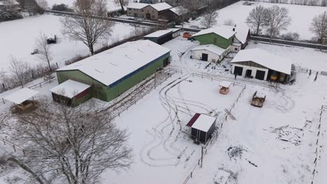 Aerial-view-of-a-snowy-farm-with-horses-in-northern-germany