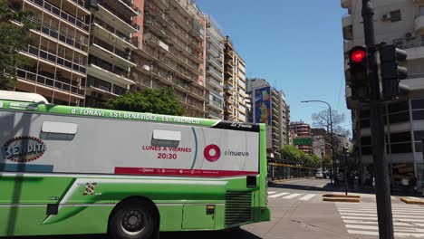 collection of argentine buses drive at palermo neighborhood, panning view of residential area in summer