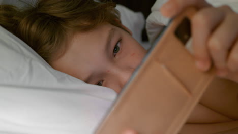 boy with smartphone in the bed after waking up