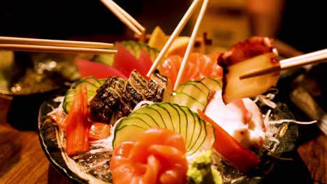 chopsticks picking sashimi from a colorful platter