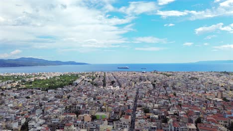 aerial wide cityscape footage of kalamata city, messinian bay on the background, blue sky with white clouds on a spring day 4k