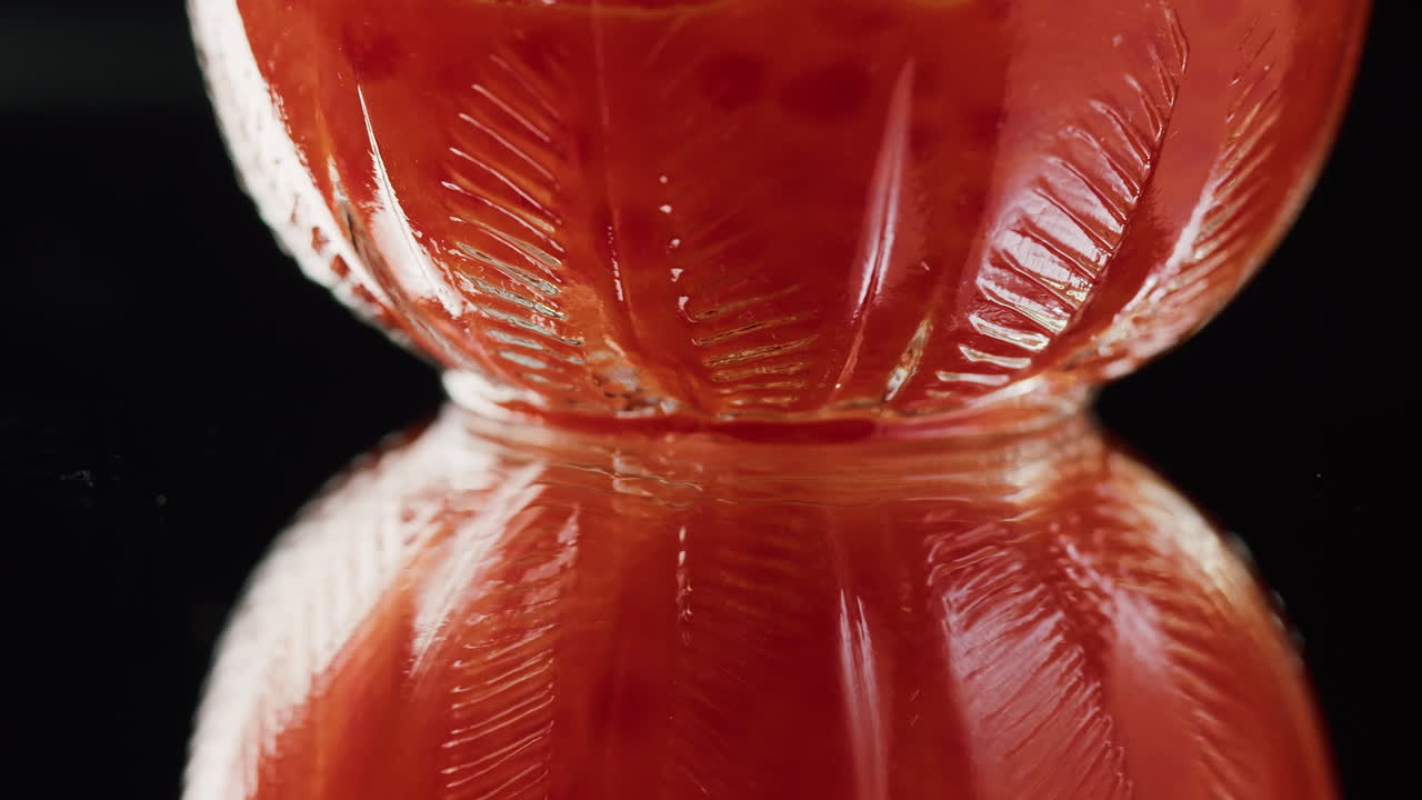 Primo piano di liquido rosso in un bicchiere strutturato che ruota con riflesso