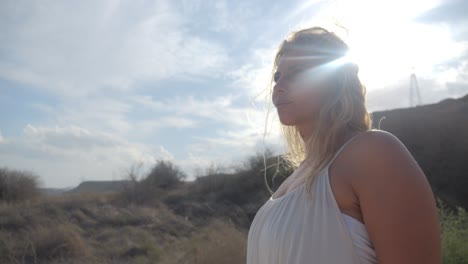 A-beautiful-woman-in-a-white-dress-walking-in-the-hills-of-Greece-in-slow-motion-with-rays-of-sunlight