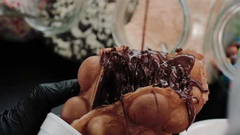 pouring melted chocolate on a waffle in a waffle baking store