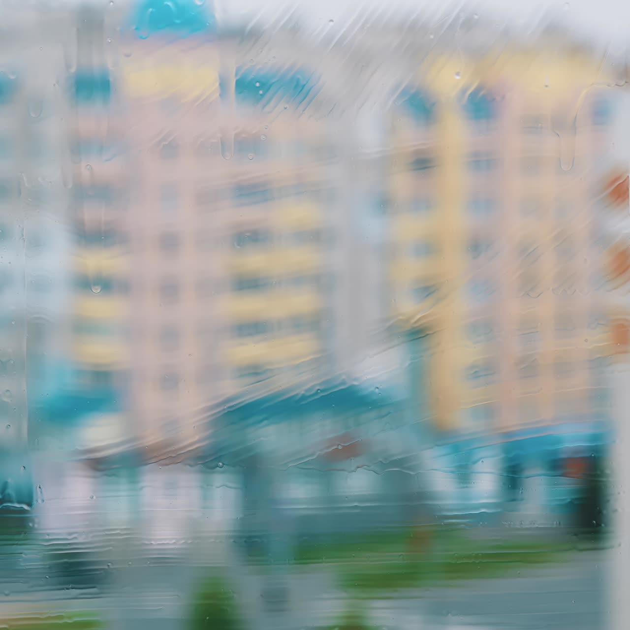 Washing a window in the city. Wet window is cleaning with special brush on blur background of multi-storey buildings