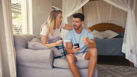 Excited-Couple-In-Bedroom-At-Home-Celebrating-Positive-Pregnancy-Test-Result