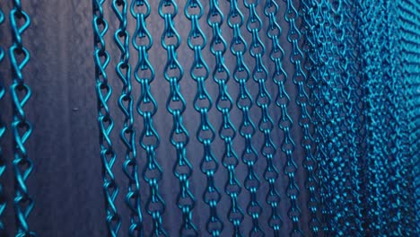 la mano pasa sobre los anillos metálicos azules del fondo de la cortina