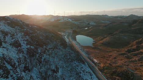 Wind-turbines-on-top-of-hill-in-Norway-and-cars-on-a-narrow-road