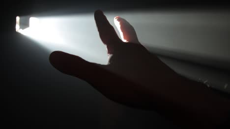 hombre sosteniendo su mano contra un rayo de luz