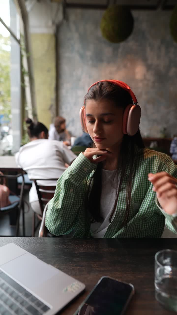mujer con auriculares, trabajando en un café