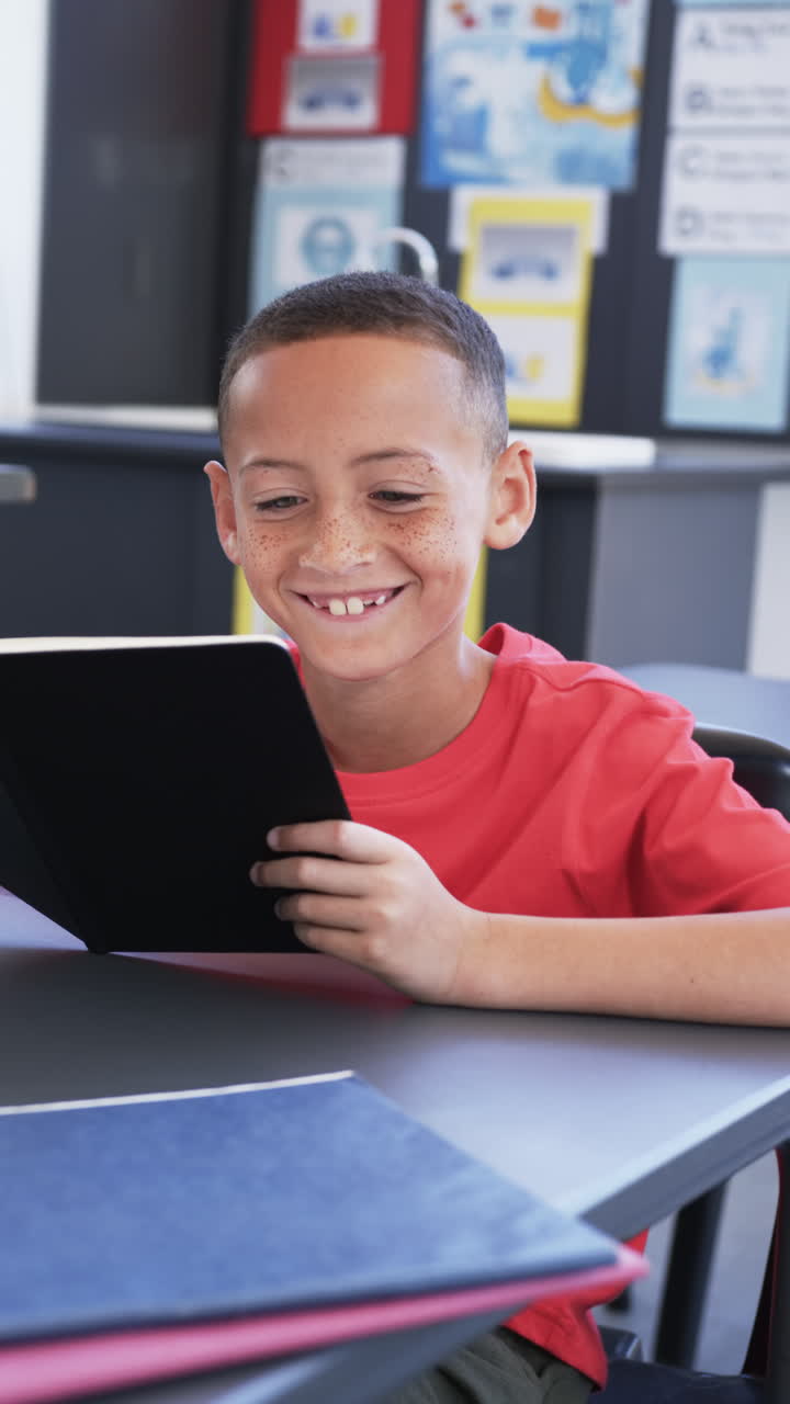 Vertical video: In school, boy reading book at desk, smiling and enjoying story
