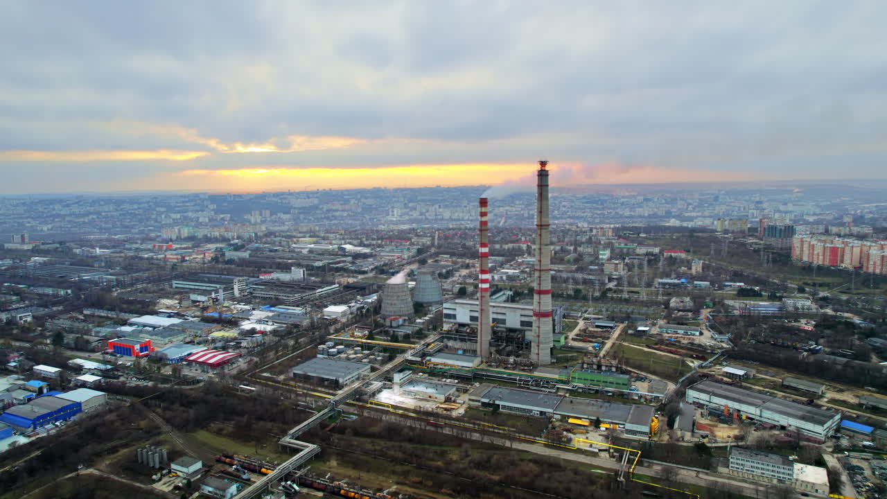 Aerial drone view of thermal power plant in Chisinau at cloudy weather, Moldova. View of pipes with felling steam, cityscape, sunset