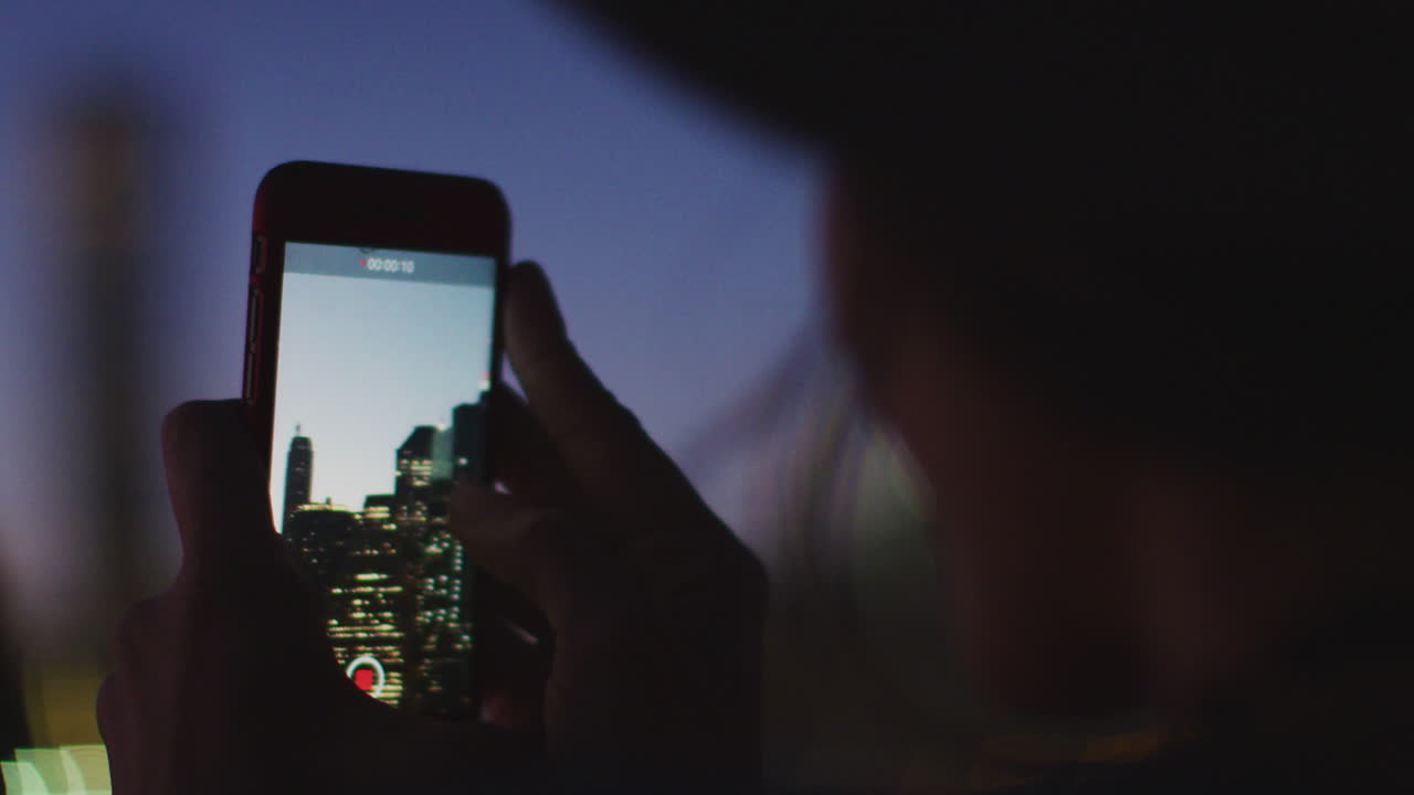 저녁에 맨해튼 스카이라인의 비디오를 촬영하는 관광객의 실루 ⁇