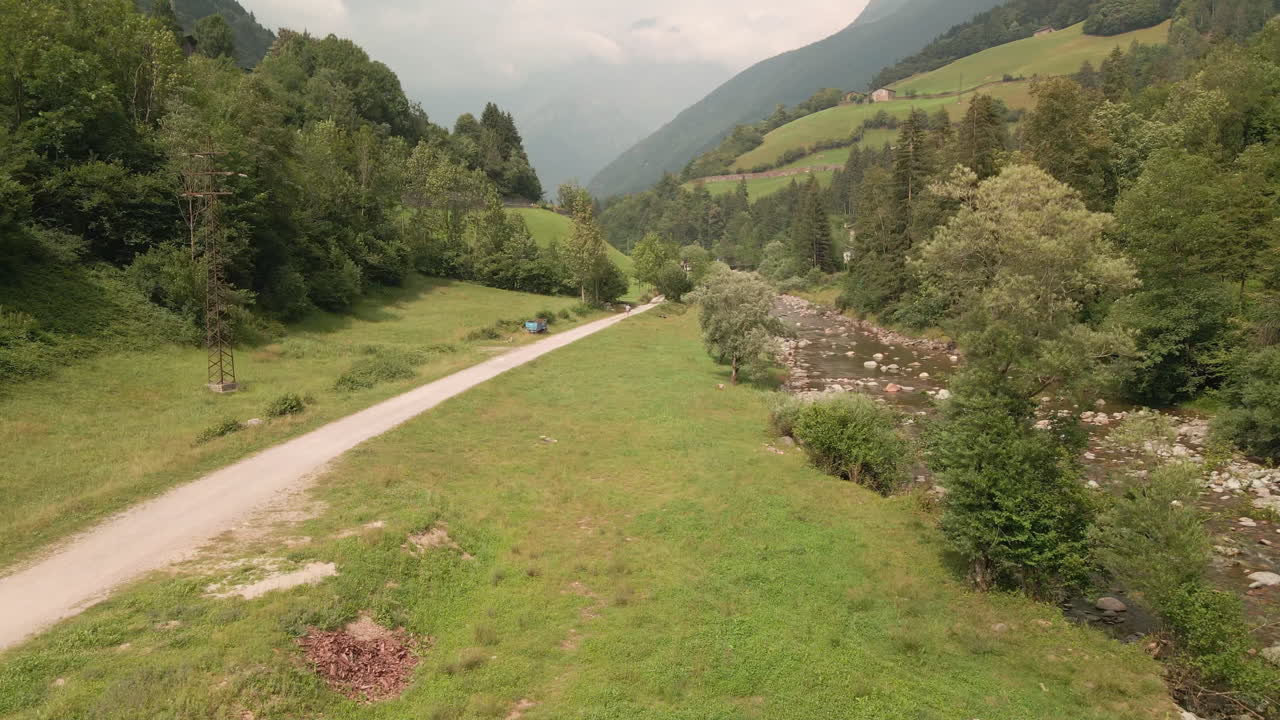 exuberante vegetación en el valle junto al río y siluetas de los alpes al fondo en el norte de italia