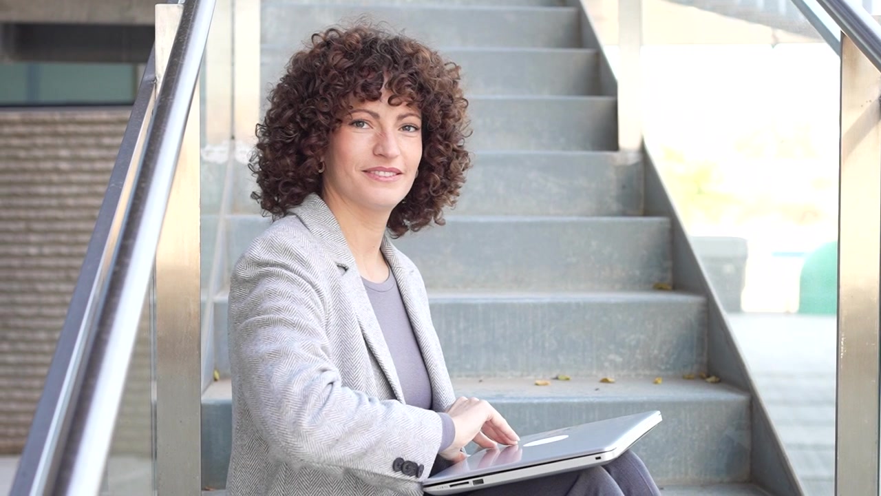 Una donna d'affari professionista lavora intensamente al suo laptop in un vivace e moderno ambiente urbano.