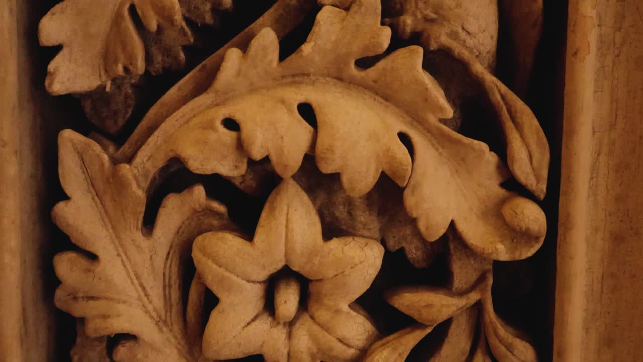 Primo piano dal basso verso l'alto di un modello dettagliato e figure scolpite nella pietra. Intagli decorativi con motivi di foglie, fiori e uccelli esotici su una parete interna decorata nel Palazzo di Monserrate a Sintra