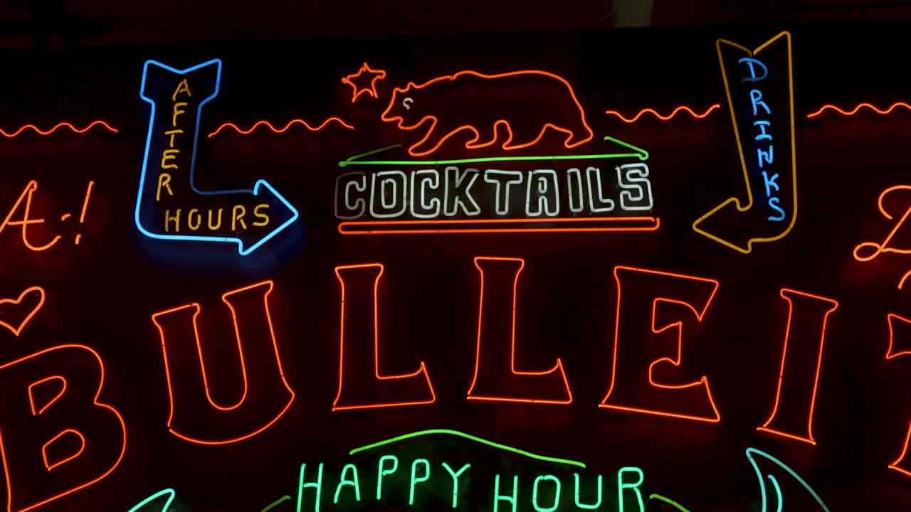 칵테일과 해피 아워를 광고하는 led 표지판이 있는 검은색 바 벽