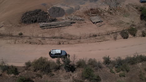 Toma-Aérea-De-4x4-Conduciendo-A-Lo-Largo-De-Un-Camino-Polvoriento-Pasando-Por-Ranchos-En-América