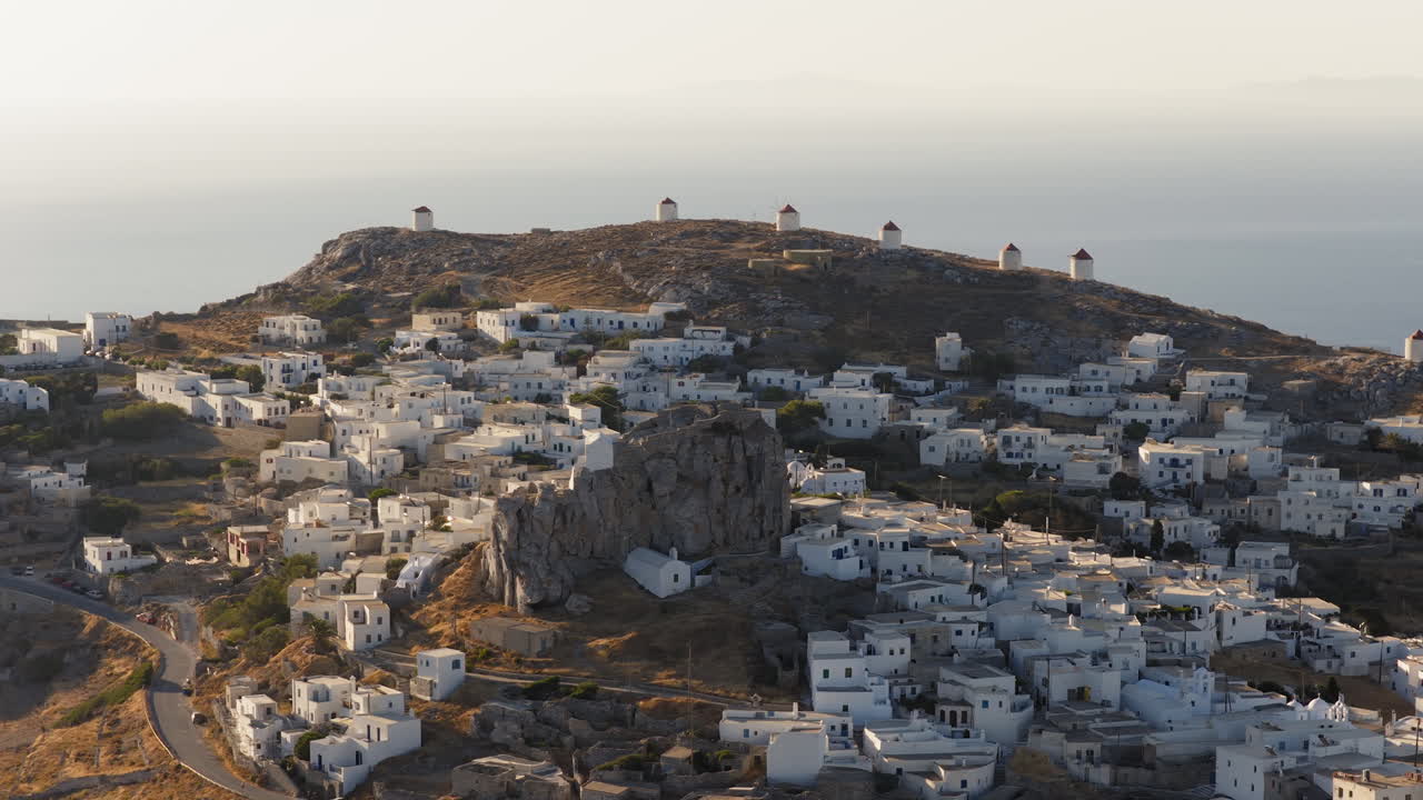 Historic windmills of Chora rise over white Cycladic village at sunrise, Amorgos island, Greece