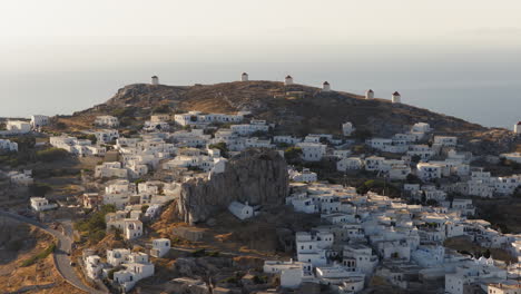 historic windmills of chora rise over white cycladic village at sunrise, amorgos island, greece