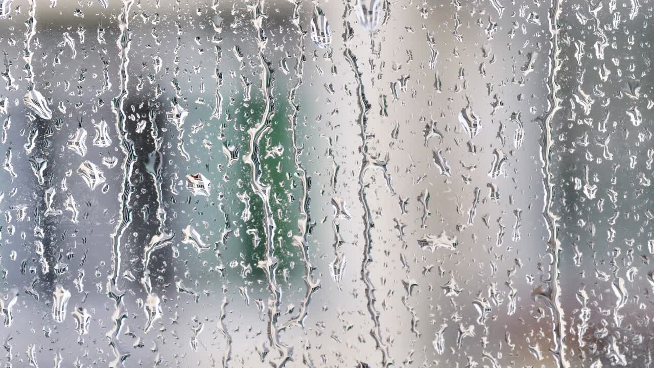 gotas de lluvia en la superficie de los vidrios de la ventana con el fondo del edificio borroso, película 4k, cámara lenta.