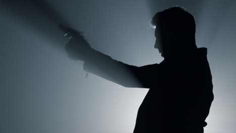 Silhouette-offender-shooting-pistol-in-darkness.-Focused-man-pulling-trigger-gun