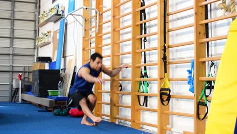 a still shot of a guy doing pistol squats inside a gymnastics gym